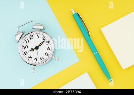 Metal vintage alarm clock with office pen on colorful paper background. Work and planning time flat lay concept Stock Photo
