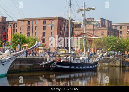 Tall ship La Mouine in Canning Dock at Liverpool waterfront, with the former warehouses of Royal Albert Dock in the background Stock Photo