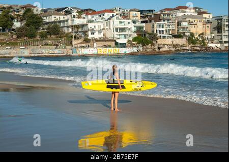 21.09.2018, Sydney, New South Wales, Australia - A young female surfer stands with her surfboard under her arm at Bondi Beach and looks out to the open sea. [automated translation] Stock Photo