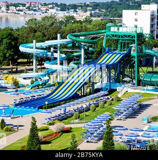 Water Park on the beach on a Sunny morning. Steep multi -colored slides and a pool at the bottom.Attractions in the form of spiral pipes. Stock Photo
