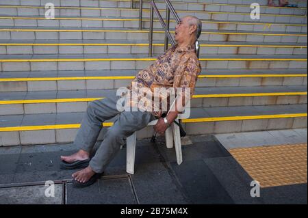 17.12.2017, Singapore, Republic of Singapore, Asia - An elderly man is sitting on a chair in Crete Ayer Square, next to the Buddha Tooth Relic Temple in Singapore's Chinatown district, taking a nap. [automated translation] Stock Photo