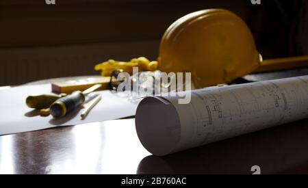 Engineer or construction manager office. Building and construction background concept. Scheme, helmet and build tools on the desk. Stock Photo