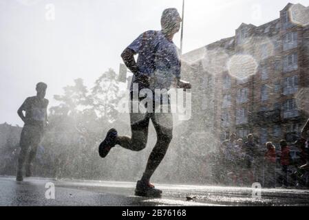 Participants in the 43rd Berlin Marathon in the Schoeneberg district of Berlin will be cooled off with a water shower. 41,283 runners participated in the marathon. [automated translation] Stock Photo