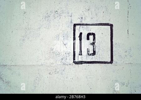number 13 painted on white house wall Stock Photo