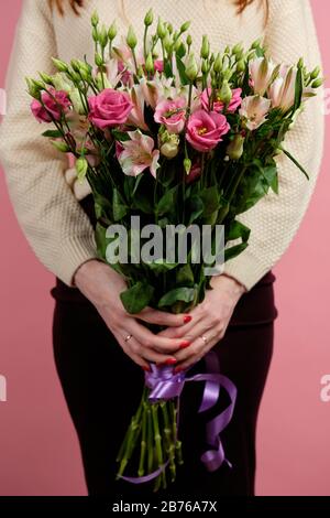 A tall bouquet of pink alstromeries and eustomas in the hands of a red-haired girl Stock Photo