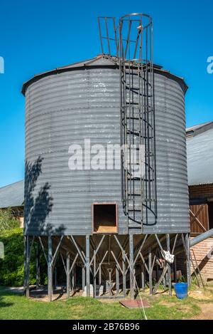 Cereal metal silo open with some seeds falling down with a blue sky Stock Photo