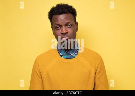 Man in yellow sweater looking bored feeling stressed after hard working day Stock Photo
