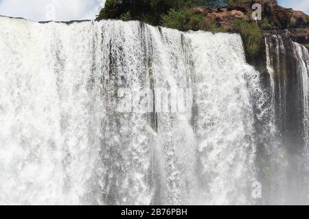 Close view of waterfall in high shutter speed photo with blue sky with a few clouds. Fall of Iguassu River located in Iguaçu National Park in Brazil. Stock Photo