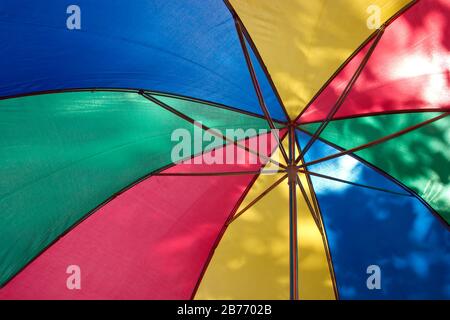 Under opened color umbrella protection on bright sunny summer day closeup Stock Photo