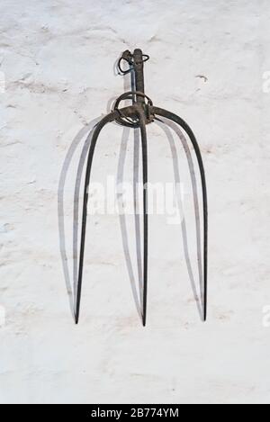 Pitchfork hanging on a white wall Stock Photo