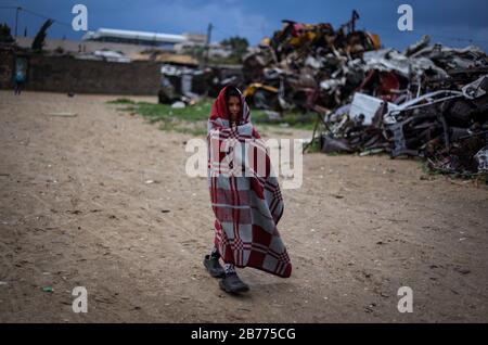 Gaza, Palestine. 13th Mar, 2020. A girl wears a blanket for warmth during a cold weather wave in the outskirts of the poor neighbourhood of Khan Yunis refugee camp. Credit: SOPA Images Limited/Alamy Live News Stock Photo