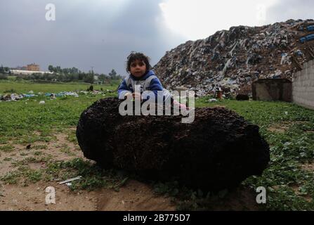 Gaza, Palestine. 13th Mar, 2020. A child plays on a huge stone during a cold weather wave in the outskirts of the poor neighbourhood of Khan Yunis refugee camp. Credit: SOPA Images Limited/Alamy Live News Stock Photo