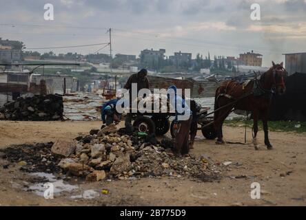 Gaza, Palestine. 13th Mar, 2020. A Palestinian man and his children searching for damaged stones for income during a cold weather wave in the outskirts of the poor neighbourhood of Khan Yunis refugee camp. Credit: SOPA Images Limited/Alamy Live News Stock Photo