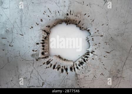 Hole made by a 30 millimeters projectile on an iron sheet Stock Photo