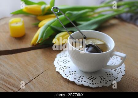 Spring morning. A cup of green tea with yellow tulips on wooden table Stock Photo