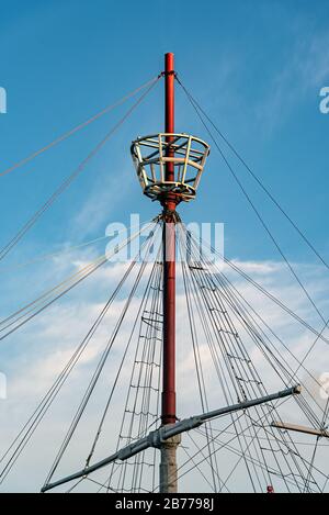 Mast of a ship with its ropes, its tail for the watch and a beautiful cloudy sky behind Stock Photo