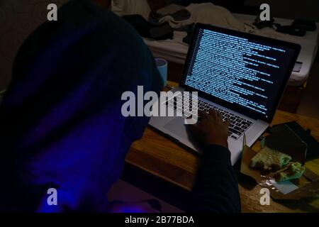 Male computer hacker in messy hotel room. Stock Photo