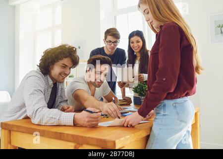 Teamwork. Young people analyze discuss business strategies while sitting at a table Stock Photo