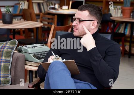 Therapist writing down notes during therapy sitting in a chair Stock Photo
