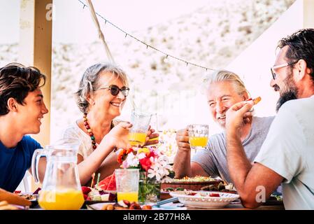 Happy and cheerful mixed ages and generations caucasian family stay together eating at lunch at home or restaurant - people enjoy fathers and son cele Stock Photo