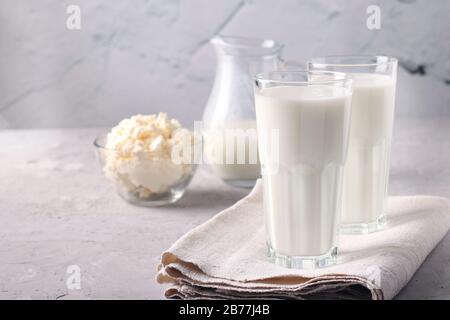 Kefir or Ayran fermented drink in a glasses and jug, as well as cottage cheese in a bowl on light gray background, Copy space Stock Photo