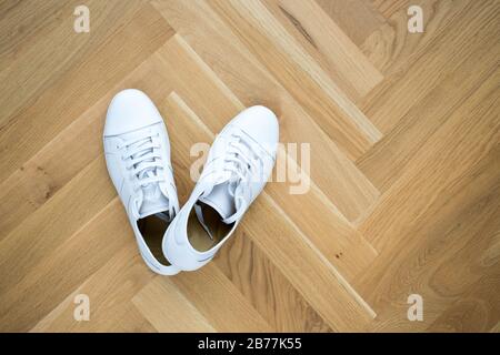 white basic leather trendy sneakers on wooden floor Stock Photo