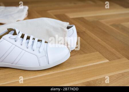 white basic leather trendy sneakers on wooden floor in bag Stock Photo