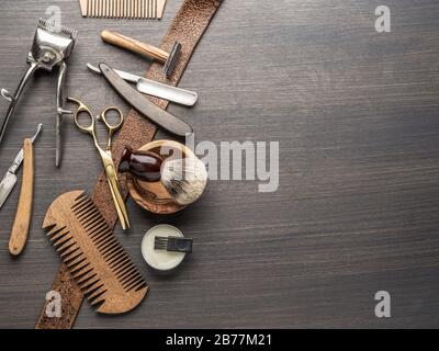 Classic grooming and hairdressing tools on wooden background. Top view on barbershop instruments  laying on dark wooden table. Stock Photo