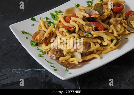 Local Italian kind of handmade pasta (strozzapreti) with seafood and tomatoes - Horizontal studio shot