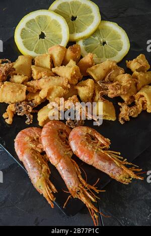 Fish fry with lemon on black stone sieve - Vertical studio shot Stock Photo
