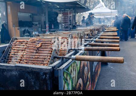 Pork meat grilling over hot coals on rotating skewers at large festival bbq stall. Yambol Bulgaria Stock Photo