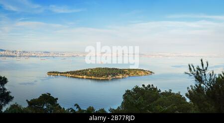 Panoramic view of Sedef Island framed by green trees from Buyukada island. Sedef Island is a neighbourhood in the Adalar district of Istanbul. Stock Photo