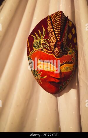 Traditional Dance Accessory: Red Indonesian Wayang Mask on a white curtain Stock Photo