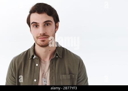 Close-up portrait of handsome macho man with beard in olive shirt, smile cheeky and looking camera with friendly, relaxed expression, standing joyfuly Stock Photo