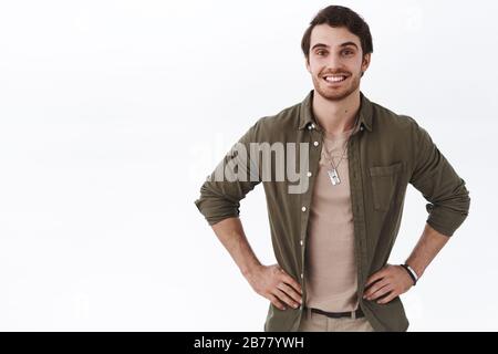 Relaxed and carefree happy smiling man with cheerful beaming smile, standing in ready pose, waiting for someone with pleased, satisfied expression Stock Photo