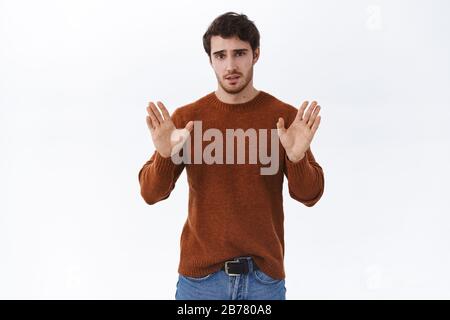 Enough, stop it. Handsome man trying to calm down friend, showing relax gesture raising hands up unarmed, solving troublesome situtation with Stock Photo