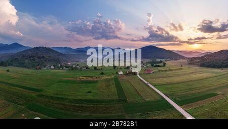 Beautiful sunset in mountains in Croatia. Bird's eye view panorama of amazing sky and the red sun lights shooting clouds over valley. Stock Photo