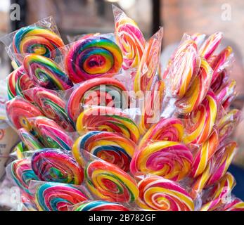 Colorful bright assorted candy canes and rainbow colored spiral lollipops with scattered marmalade, jellybeans and different colored round candy. Stock Photo
