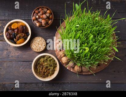 Happy Nowruz holiday background. Celebrating  various dried fruits, nuts, seeds, light background with green grass wheat, copy space top view Stock Photo