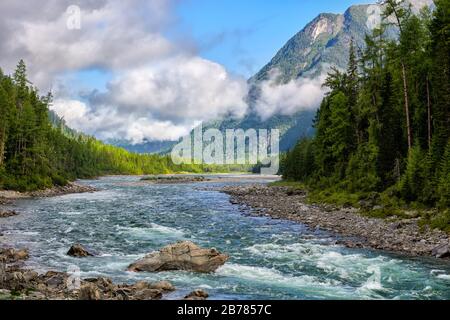 Low scattered clouds over a tumultuous small river in the mountains. August morning on amazing nature. Boreal forest near a rivulet in Eastern Siberia Stock Photo