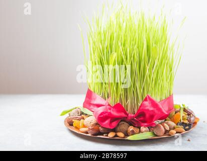 Happy Nowruz holiday background. Celebrating  various dried fruits, nuts, seeds, color  background with green grass wheat, copy space top view Stock Photo