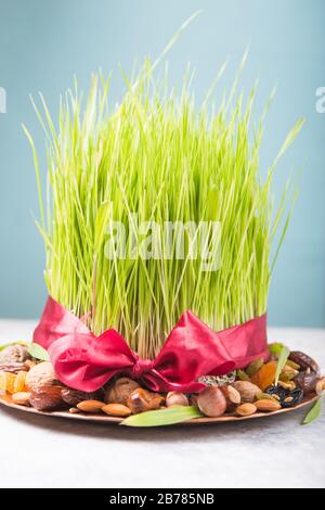 Happy Nowruz holiday background. Celebrating  various dried fruits, nuts, seeds, color  background with green grass wheat, copy space top view Stock Photo