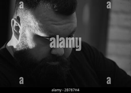 Close up portrait brutal professional Barber cuts hair to client in barbershop. Man with a beard and a modern haircut in the process of work. Concept Stock Photo