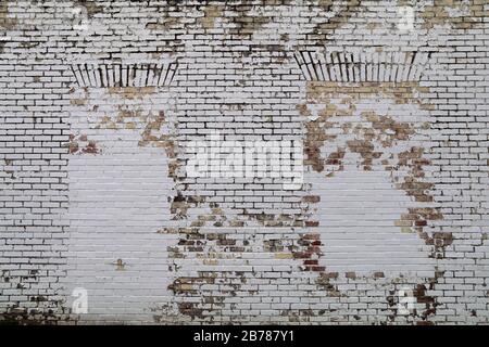 a brick wall with blocked windows painted white and faded Stock Photo