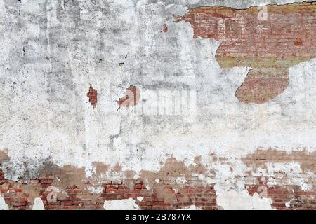 a faded white cracked stucco and red brick garden wall Stock Photo