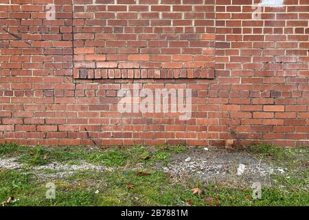 an ornate red brick back garden wall with grass patch path Stock Photo
