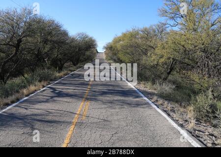 an old cracked two lane desert road leading into the horizon Stock Photo