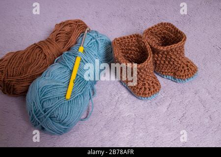 Knitted boots. Knitted shoes. Booties for babies. Made by hands. Stock Photo