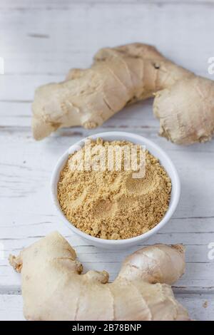Grounded ginger and ginger root on white wooden surface. Stock Photo