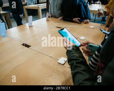 Paris, France - Nov 3, 2017: Overhead view of customers admiring inside Apple Store the latest professional iPhone smartphone manufactured by Apple Co Stock Photo